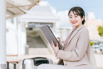 出張先の駅・空港から配車アプリでタクシー・レンタカーを手配する女性（レンタカー・ライドシェア）
