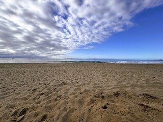 Fototapeta na wymiar sandy beach on the coast with blue sky and clouds