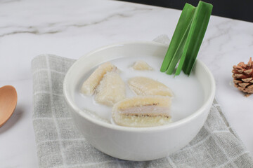 Banana in coconut milk or Kluay Buad Chee with pandan leaf in white bowl. Popular food Thai traditional sweets or snack.