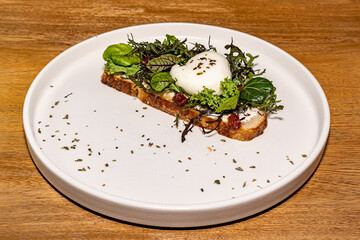 French toast with salad and poached egg, gourmet hotel restaurant. Wooden table.