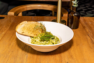 Green pasta with parmesan cheese and spiced bread. Pesto and spinach. Gourmet hotel restaurant.