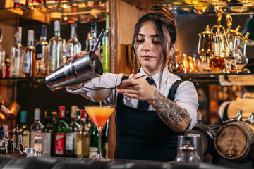 Female bartender preparing a cocktail in a traditional cocktail bar