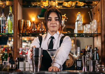 Young bartender offering a drink at the bar of a cocktail bar
