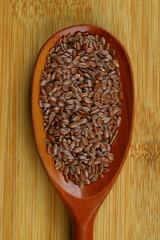 Flax seeds. Flaxseed powder in a wooden spoon. Standing on a Wooden background.