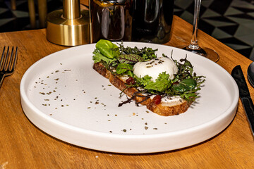 French toast with salad and poached egg, gourmet hotel restaurant. Wooden table.