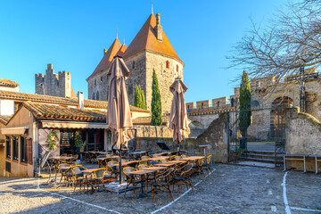 Empty shops and sidewalk cafes at winter inside the La Cite' walls of the medieval castle at...