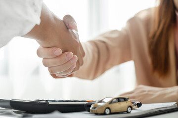 Businesswoman and brokers shake hands after completing negotiations to buy Car insurance and sign contracts. Car insurance concept