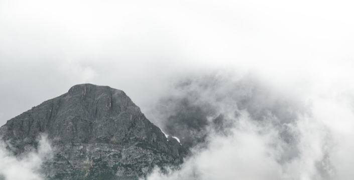 Rocky Mountains surrounded by clouds and mist.  The mist fades to transparent as you move towards the top right corner.
