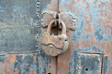 Old, metal padlock locking an iron gate