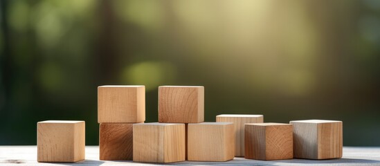 Wooden blocks neatly stacked on a table, illuminated by sunlight filtering through the surrounding trees - obrazy, fototapety, plakaty