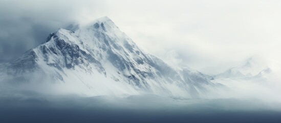 Majestic snowy mountain peak shrouded in clouds, creating a serene and picturesque scene in nature