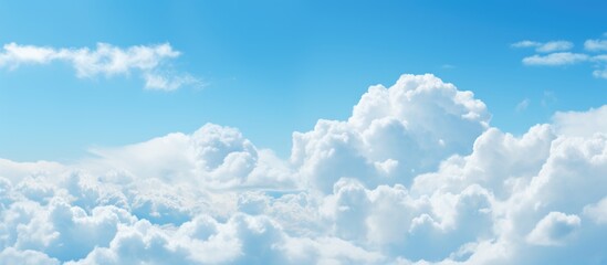 The image shows a distant plane navigating through a serene blue sky adorned with fluffy white clouds - obrazy, fototapety, plakaty