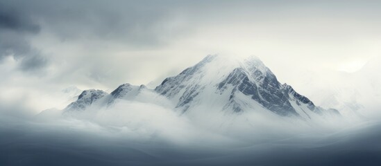 Snow-covered mountain summit shrouded in clouds, creating a serene and mystical atmosphere