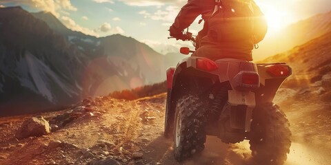 A man is driving an atv on a dirt road. The sun is setting in the background