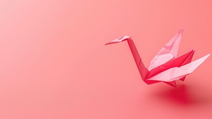 Pink origami crane on matching background with ample copy space