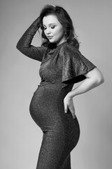 Black and white portrait of young pregnant female in grey sequin dress. - 781014105