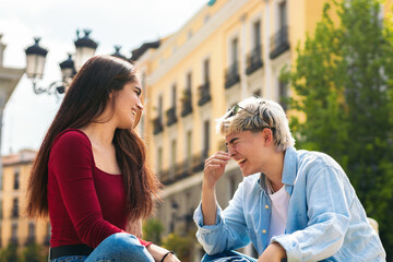 two teenager girls sitting talking and laughing