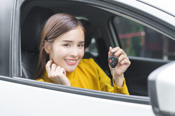 Dealership automobile, happy smile asian young woman sitting in new a car after purchase, rent success, showing, holding auto remote key of vehicle, owner driver guy buy gift for yourself at showroom. - obrazy, fototapety, plakaty