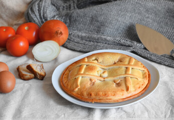 Freshly cooked round empanada on a background of fabrics in nude tones