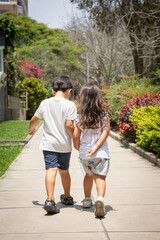 Two little siblings walking in a park