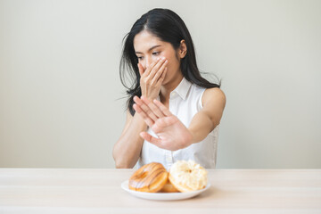 Diet concept, asian young woman hand push out, deny sugar donut, doughnut and sweet taste food on...