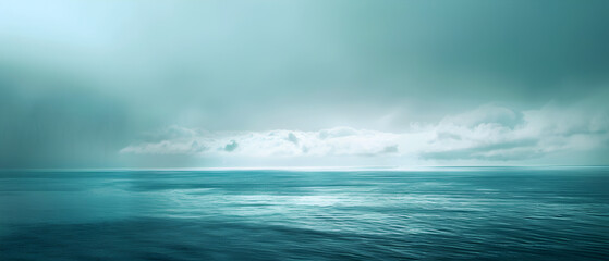 A calm ocean with a cloudy sky in the background. The sky is a mix of blue and gray, giving the scene a serene and peaceful atmosphere