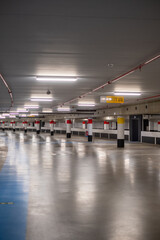 This image portrays the quiet vastness of an empty underground parking lot. The polished concrete...