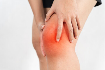 A person with a red knee is holding their knee.