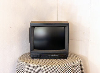 A small old television on a round table in the corner of the room