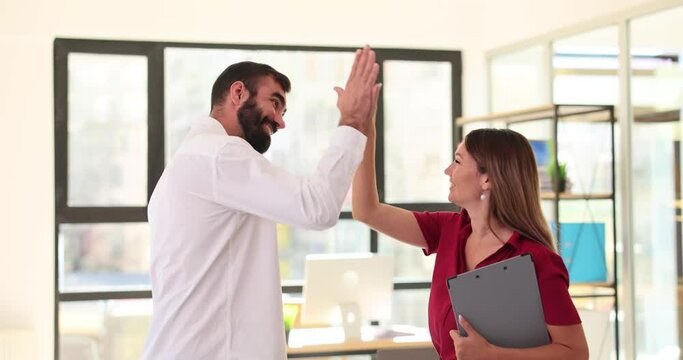 Successful businessman and woman giving high five in office