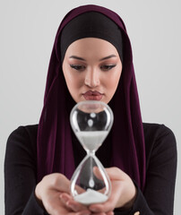Beautiful arab businesswoman wearing hijab and holding sand clock. Time is passing and it's a pressure concept. - 781034909