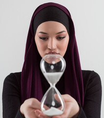 Beautiful arab businesswoman wearing hijab and holding sand clock. Time is passing and it's a pressure concept. - 781037576