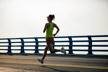 Fitness woman runner running on seaside bridge