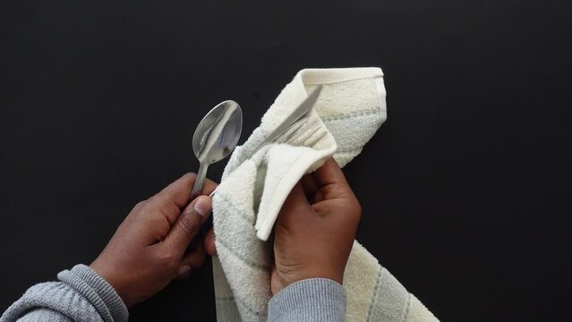  person hand cleaning and drying cutlery with a towel