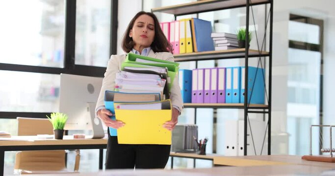 Office employee carries heavy folders in office