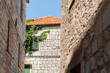 Terracotta tile roof over stone exterior wall beyond two stone walls