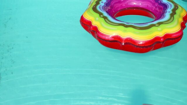 The wind moves the colorful inflatable ring on the surface of the pool
