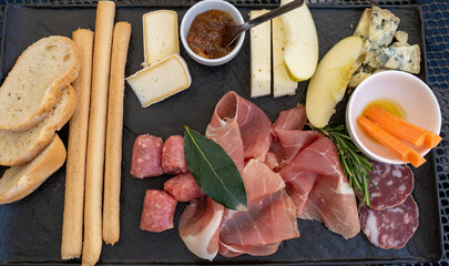 Traditional Italian food. Mix of typical cheeses and cold cuts on a stone plate