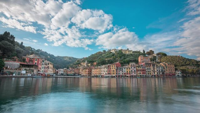 Timelapse view over harbor of clouds in blue sky flying over scenic Portofino