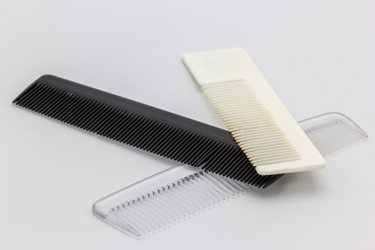 Three different colored combs on a white background. All three of the combs are plastic. 