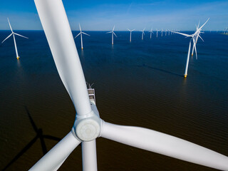 A group of majestic wind turbines stand tall in the ocean, gracefully harnessing the power of the wind to generate clean energy in Flevoland, Netherlands during the vibrant season of Spring.