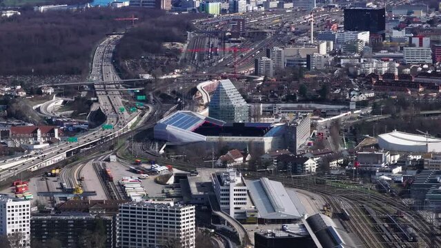 Aerial view of modern football stadium and busy multilane highway leading around. Large railroad yard in background. Basel, Switzerland