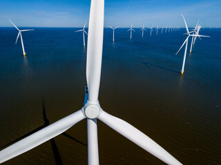 A cluster of towering wind turbines stands tall in the ocean, their blades gracefully spinning in the spring breeze, harnessing the power of the wind to produce clean energy.
