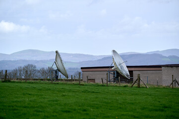 Two old satellite dishes in green field in England