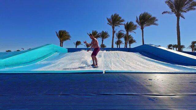 Man surfing on an artificial wave in slow motion with wipeout