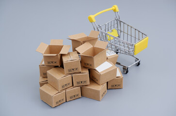 Shopping cart and carton boxes on gray background. 	