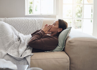 Sick woman, sneeze and blowing nose with illness, flu or cold on living room sofa at home. Young...