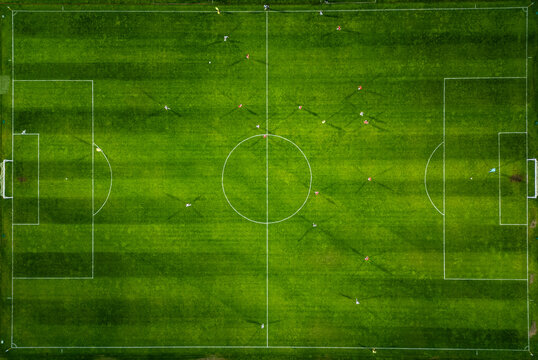 Aerial view of a soccer field in action, with players running, passing, and scoring goals.