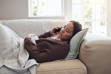 Sick woman, tissue and phone call with flu for help, advice or recovery on living room sofa at...