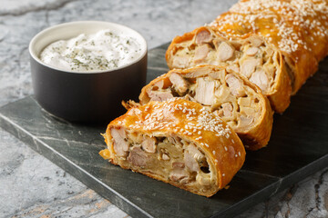 Chicken strudel with mushrooms and cheese served with sauce close-up on a board on the table....